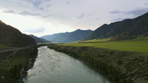 River in a Field Against the Background of a Mountain