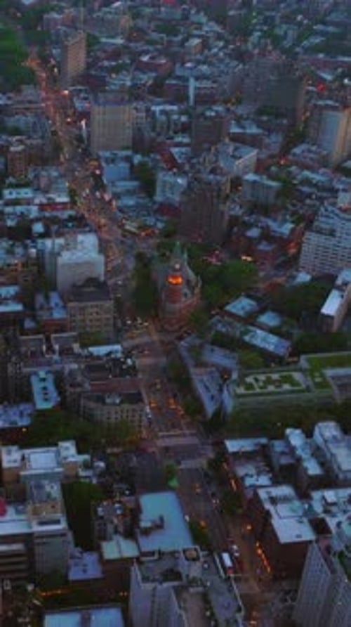 Numerous car with their lights on move by the road of New York.