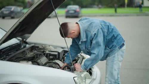 Man in Denim Jacket Inspecting Car Engine