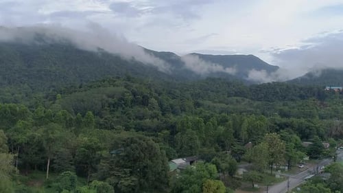 Ascending drone shot of green lush mountains with clouds on top Cropped