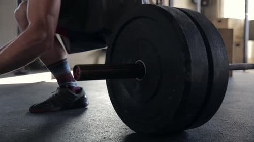 Close Up Man Loading Weight Plates Onto Barbell at Gym 3539 Years
