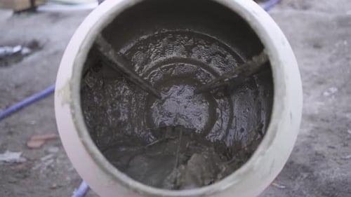 Close up of concrete mixer spinning with cement and rocks inside in slow motion