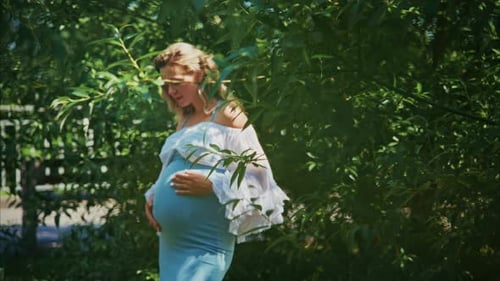 Pregnant Woman Gently Caressing Belly in Green Garden