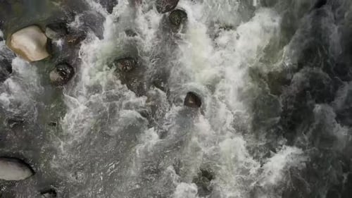 White water rapids flowing quickly down a rocky riverbed. Aerial shot.
