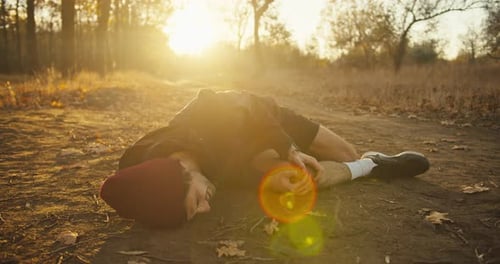 Sad Tired Guy Athletes in a Red Cap in a Black Sports Uniform Falls to the Ground While Hurting His