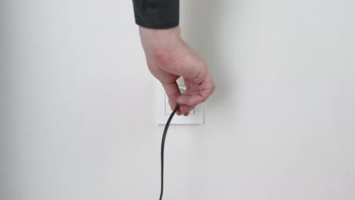 Plugging Cord Into Electrical Outlet on White Wall