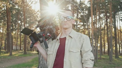 Man Holding Camera in a Sunlit Forest