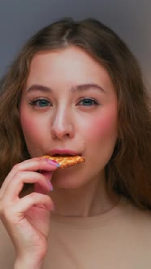 Young Woman Eating Cracker in Close Up Studio