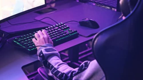 Young Gamer Sits in Gaming Chair and Plays Video Game at ESport Club