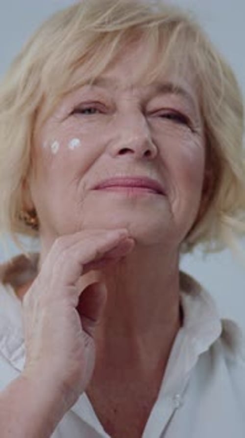 Senior Woman Applies Face Cream in Close Up
