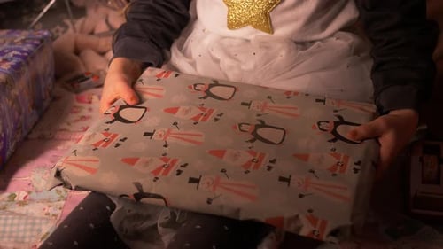 little girl putting self wrapped Christmas gift or birthday present by side fast. Close Up of Child