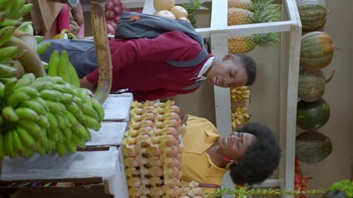 Vertical View Of A Woman And Boy Inside The Fruit Stall In The Kampala Market In Uganda, Africa. Clo
