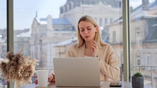 Young Woman Coughing at Table with Laptop
