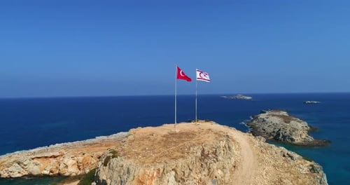 Flags Wave on Rocky Island Coastline Aerial