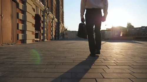 Man with Briefcase Walks along City Street
