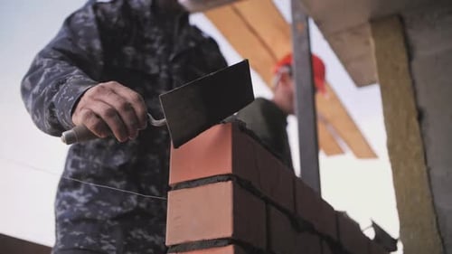 Der Baumeister legt eine Mauer aus Ziegeln an