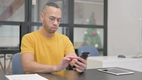Young Adult Using Smartphone at Office Desk