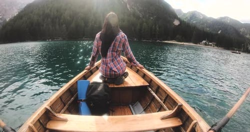 POV of a man rowing a wooden boat rowing in the middle of the lake and watching his wife smile and