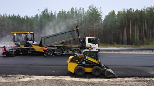 Road works on the track. Workers lay new asphalt using equipment. Roadbed repair