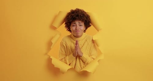 Young Woman Poses Through Torn Yellow Paper