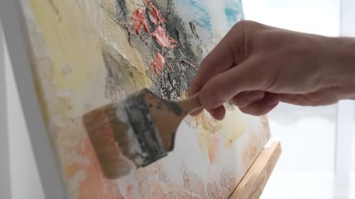 Hand Holding Brush Adding Paint to Canvas