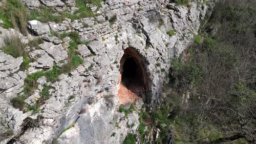 A Drone Flies Close to a Deep Cave in a Mountain Going Far Into the Rock