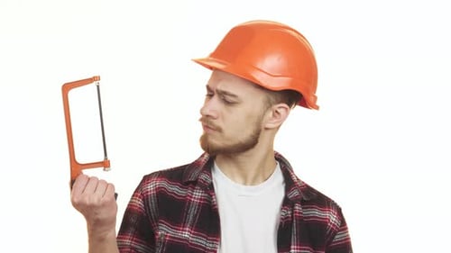 Young Handyman Thoughtfully Selecting Between Two Saws for His Next Project