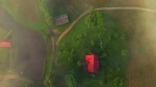 Top view of farm houses. Green fields with lakes. Drone flight above the clouds