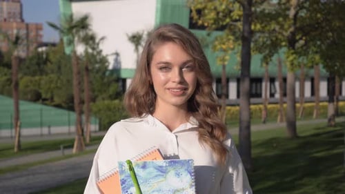 Happy Student or Schoolgirl on a Sunny Day Against the Backdrop of a School or College