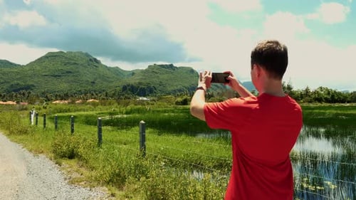 Young Adult Taking Pictures of Tropical Mountain Vista