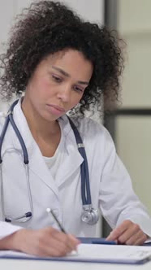 Female African Doctor Writing on Paper, Vertical Video