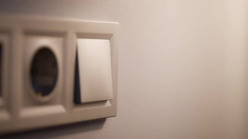 Mãos de mulher ligando e desligando um interruptor de luz de parede