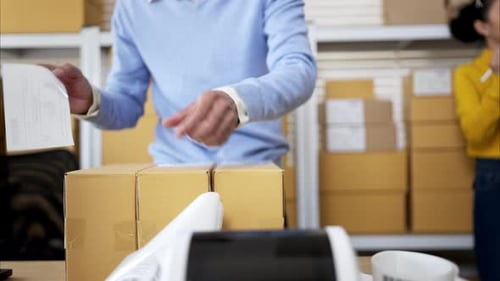 Kleinunternehmer packen gemeinsam Kartons und bereiten Versandetiketten im Lagerbüro vor