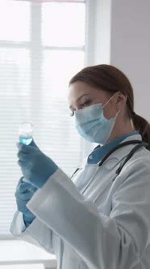 Woman Doctor Examines Vial of Blue Liquid