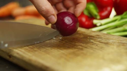 Knife Cuts Red Onion on Wooden Cutting Board