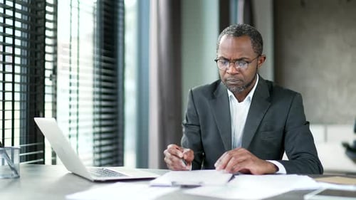 Focused Professional Reviews Documents in Modern Office