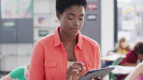 Portrait of diverse female teacher and schoolchildren at desks in school classroom