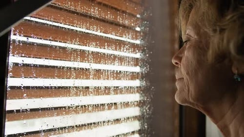 Worried Woman Is Watching The Rain From The Window At Home