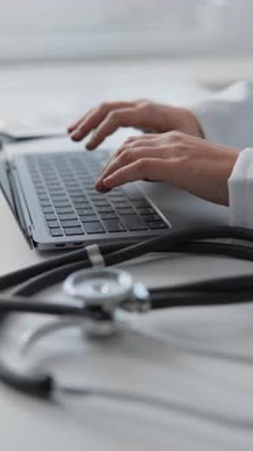 Young Female Doctor Working on Her Laptop in Clinic Recording Patients' Medical Data A Doctor with a