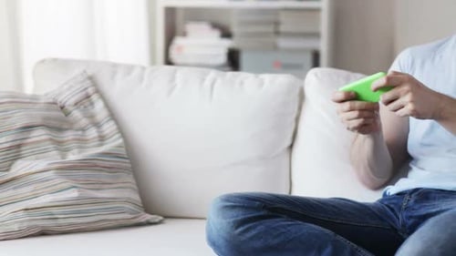 Man sitting on couch playing mobile phone game