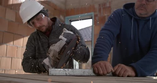 Construction Workers Cutting Metal with Grinder Indoors