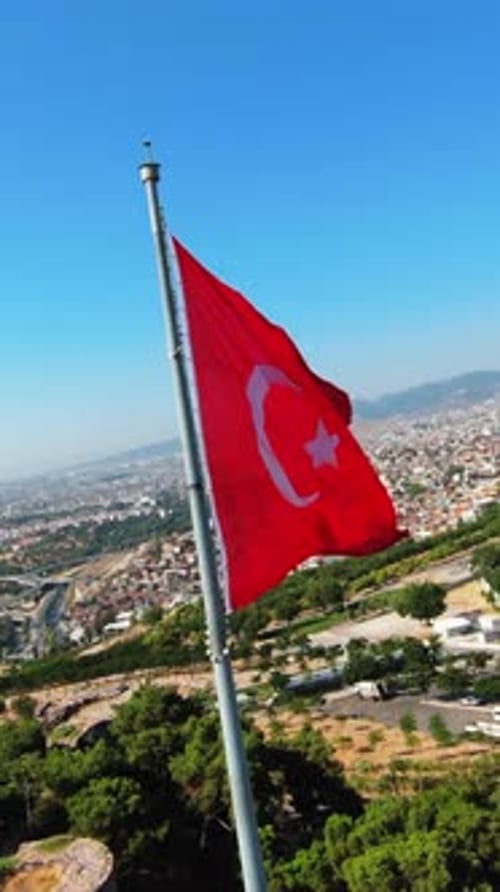 Flag Waving Overlooking City on Sunny Day