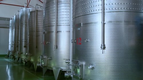 Reihe großer Gär- und Lagertanks aus Edelstahl in einer modernen Weinproduktionsfabrik
