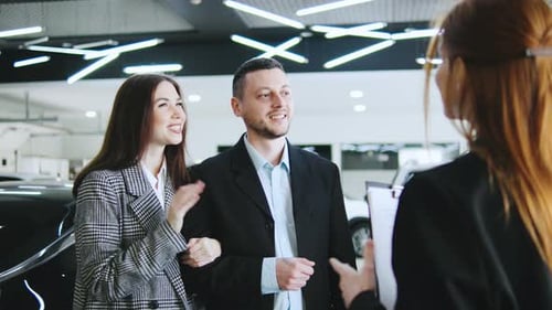 A Saleswoman Engages with a Couple at an Automobile Dealership Discussing Credit Options and
