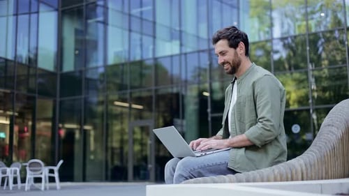 Man Working on Laptop Outside Modern Building