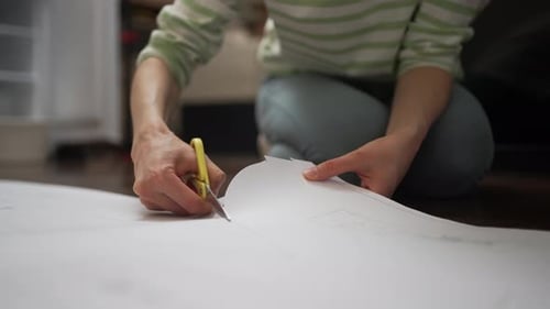 Woman Cutting Paper on Floor at Home