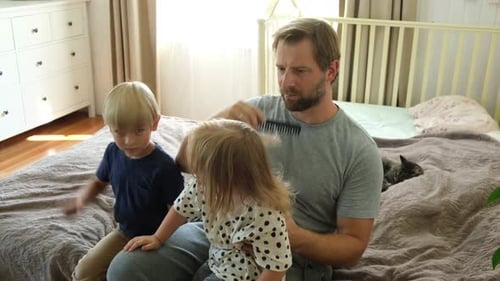 Father Brushing Daughter's Hair on Bed