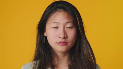 Close up, young woman looking at camera isolated over yellow background in studio