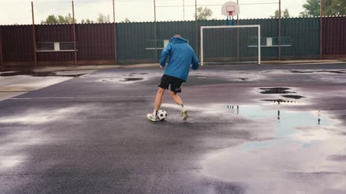 Man Playing with Soccer Ball on Wet Court