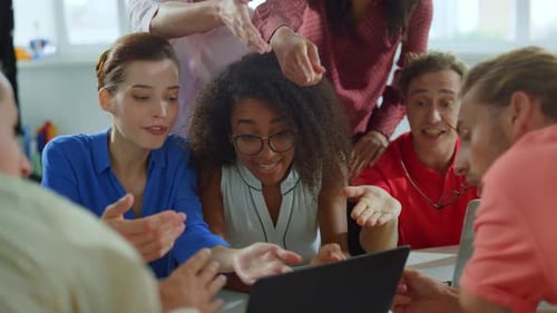 Enthusiastic Team Collaborating on Laptop in Modern Office